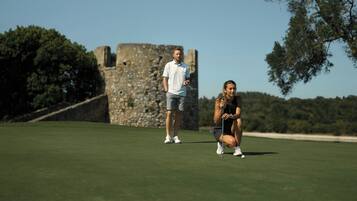 A golf course with a stone structure in the background.