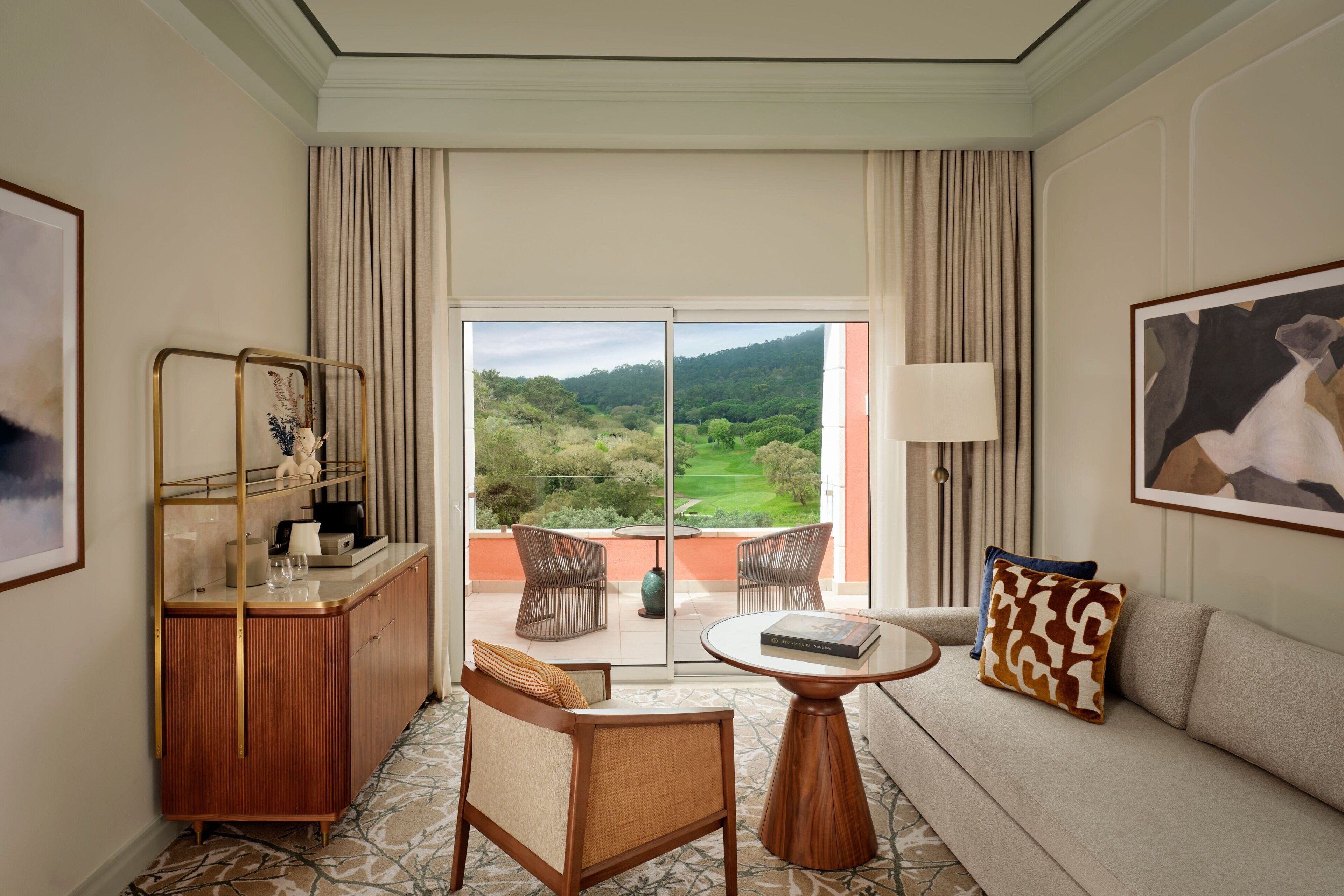 Habitación de hotel con balcón, sofá, una silla, una mesita y un armario.