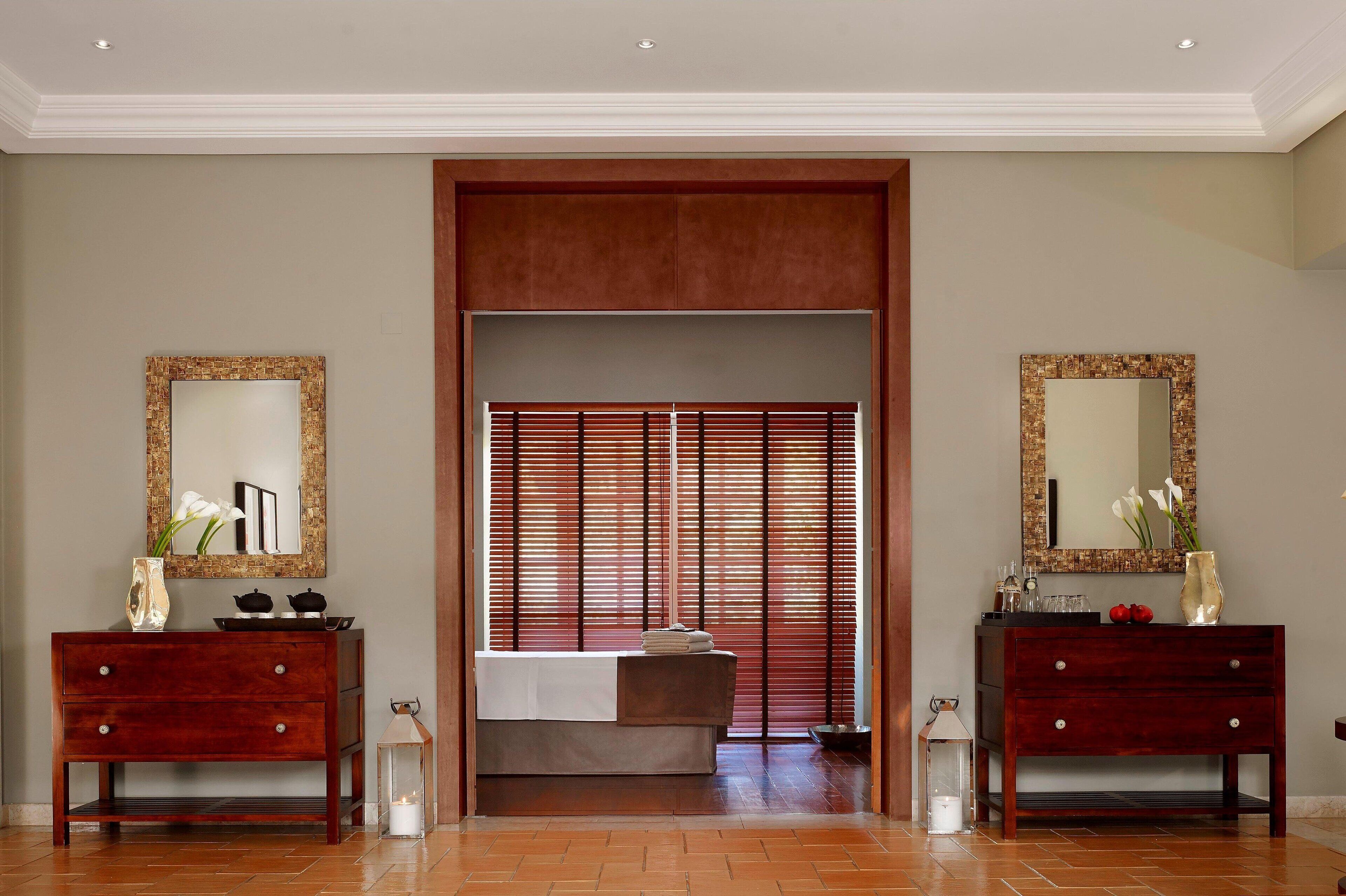 Habitación de hotel con tocador de madera, cama con cubrecama blanco, espejo grande y un panel corredero estilo shoji.