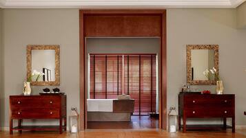 Habitación de hotel con tocador de madera, cama con cubrecama blanco, espejo grande y un panel corredero estilo shoji.