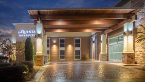 A hotel entrance with a covered walkway, a sign reading "La Quinta Inn & Suites", and a brick facade. - La Quinta Inn & Suites by Wyndham Chattanooga - East Ridge (Chattanooga)