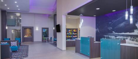 A modern lobby with a reception desk, seating area, and a large mural.