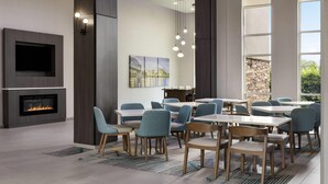 A modern dining area with tables and chairs, a fireplace, and a large window with a view. - La Quinta Inn & Suites by Wyndham Chattanooga - East Ridge (Chattanooga)
