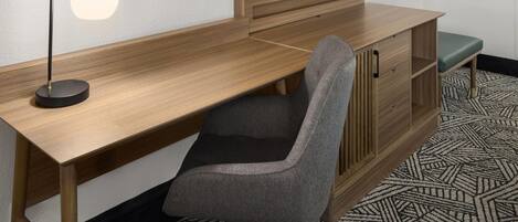 Un escritorio de madera con una silla, un televisor y un espejo.