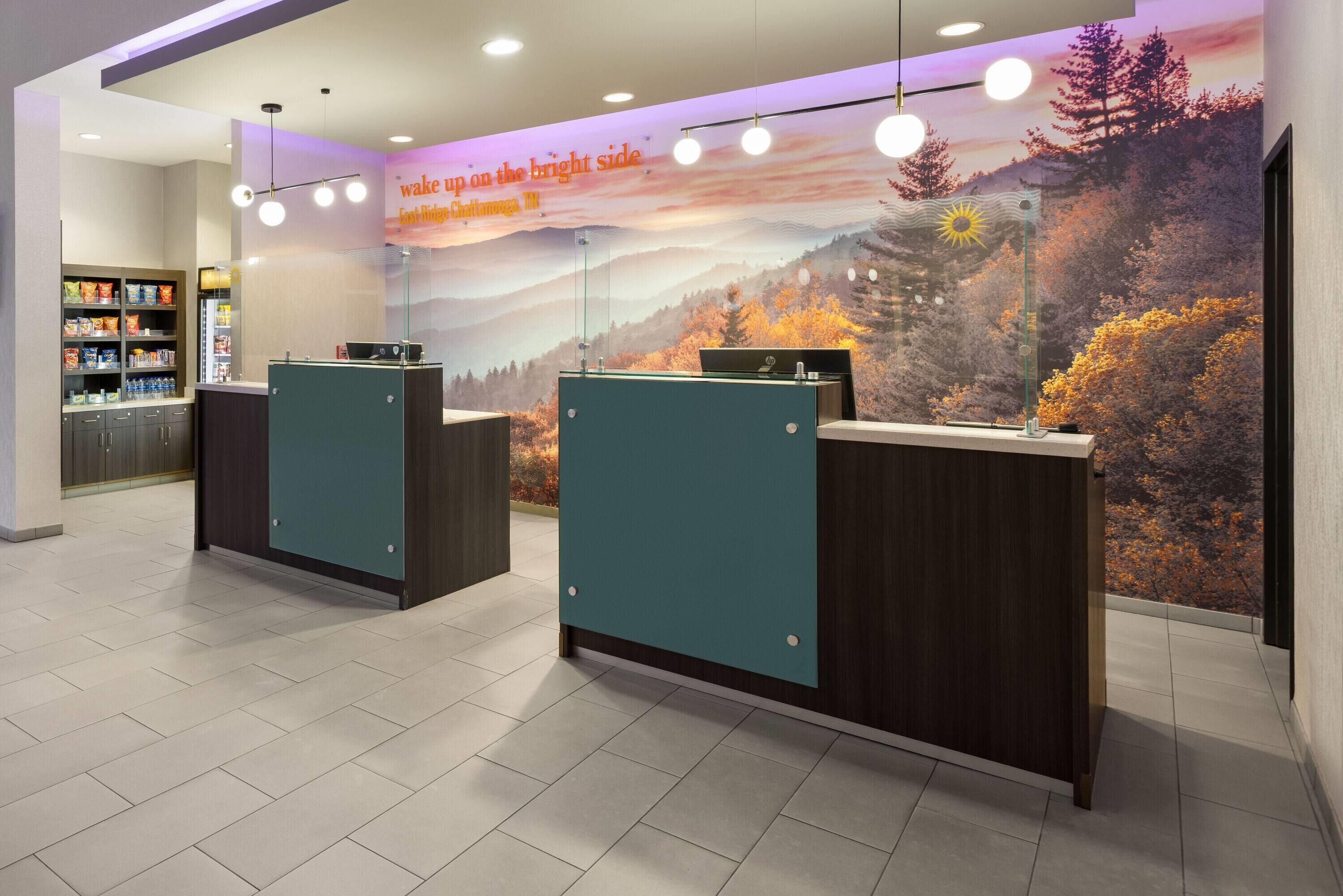 A reception area with two counters, a wall mural, and a shelf with snacks.