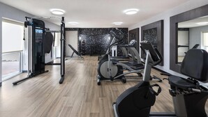 A modern gym with cardio machines, a weightlifting area, and large windows. - La Quinta Inn & Suites by Wyndham Chattanooga - East Ridge (Chattanooga)