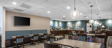 A restaurant with booths, tables, and hanging light fixtures.