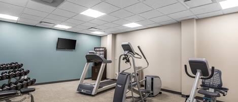 A fitness room with treadmills, an elliptical, and dumbbells.