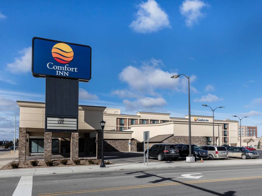 Een Comfort Inn hotel met een opvallend bord, een parkeerplaats en een helderblauwe lucht.