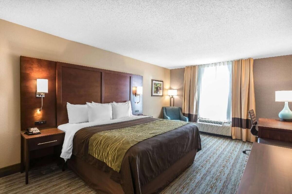 A hotel room with a large bed, bedside lamps, a desk, and a chair.