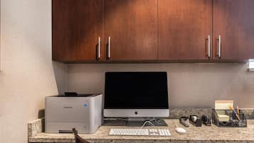 A home office setup with a desktop computer, printer, keyboard, mouse, and various office supplies on a granite countertop.
