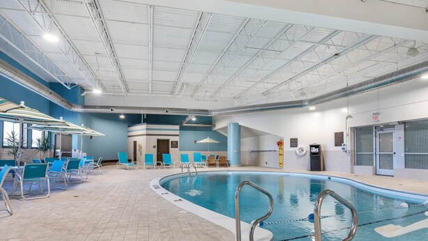 Una piscina interna con sedie blu e una postazione di salvataggio.