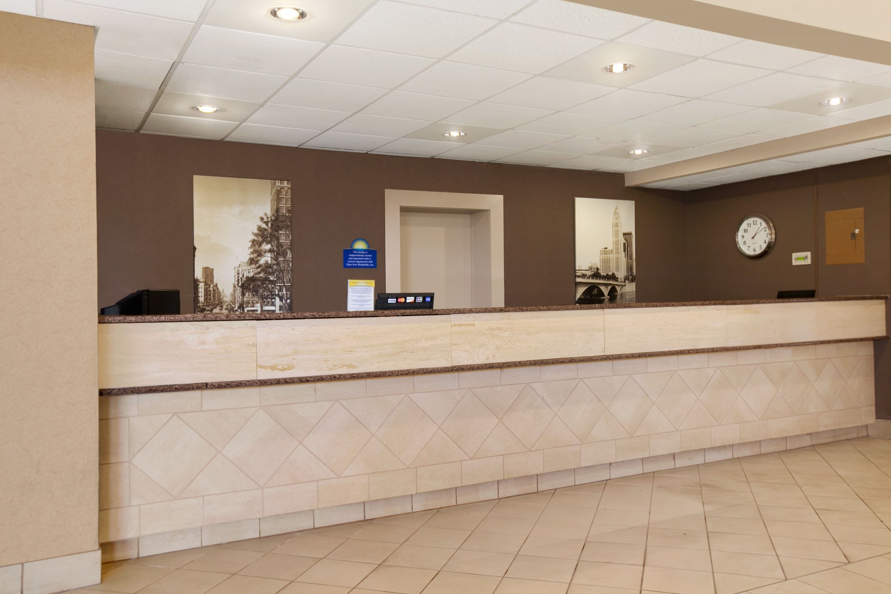 A hotel reception area with a marble counter, a clock, and a door leading to another room.