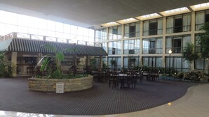 A spacious indoor area with a covered seating area, large windows, and a stone planter with plants. - Days Inn by Wyndham Columbus Airport (Columbus)