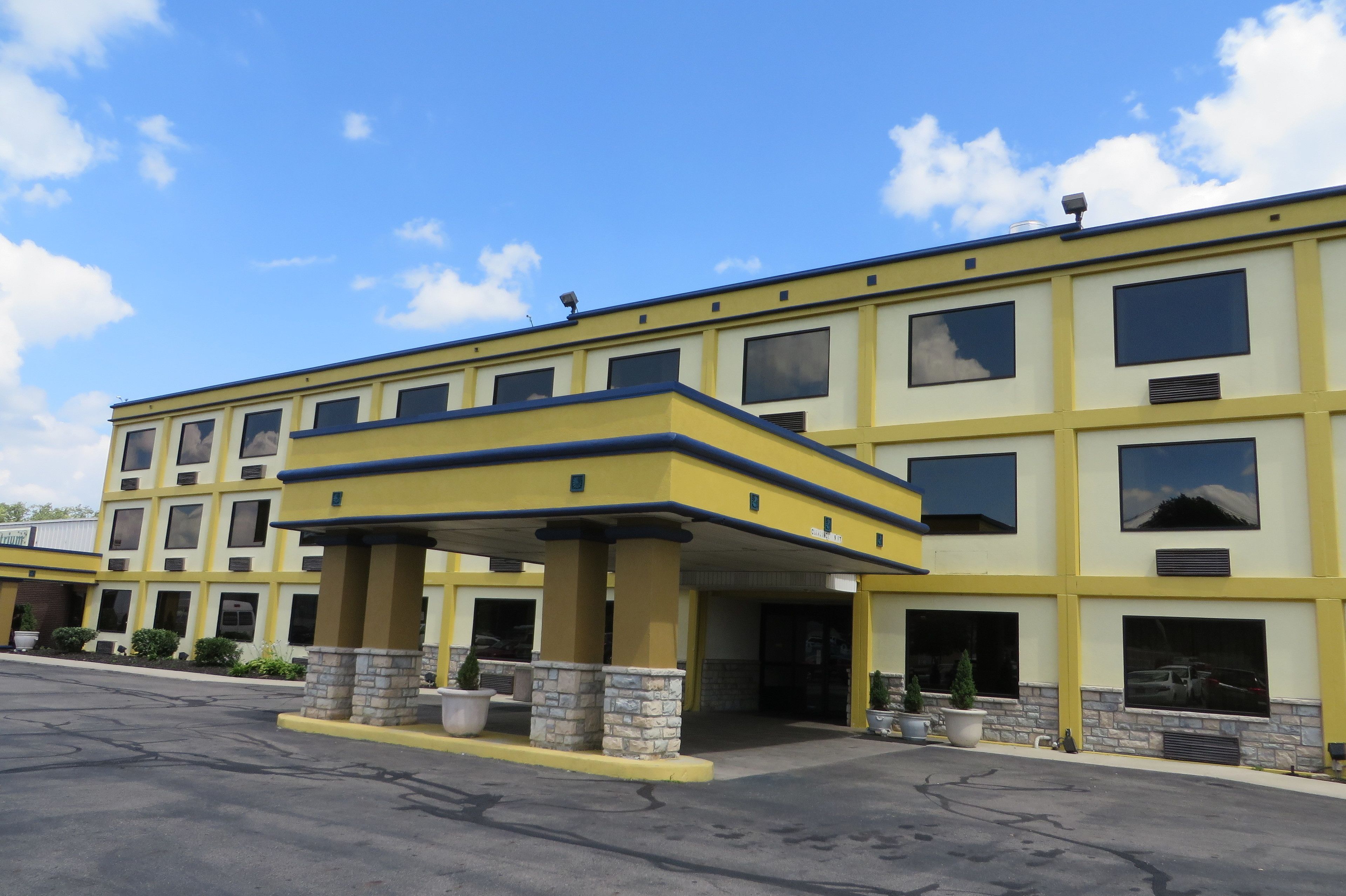 A multi-story hotel with a yellow facade and a covered entrance area.