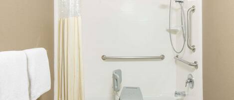 A bathroom with a bathtub, grab bars, a showerhead, and a towel rack.