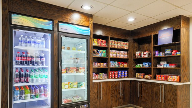 A vending area with two beverage dispensers and shelves stocked with snacks and beverages. - Holiday Inn Express Burlington by IHG (Burlington)