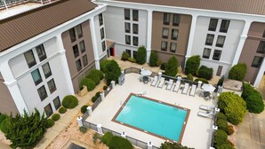 A rooftop pool area with a rectangular pool, surrounded by lounge chairs and umbrellas, and bordered by a low fence. - Holiday Inn Express Burlington by IHG (Burlington)