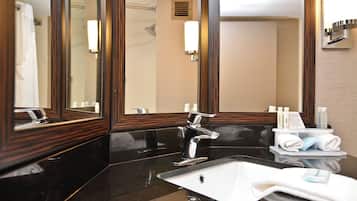 Un baño moderno con un espejo grande, una encimera negra, un grifo cromado y un lavabo blanco.