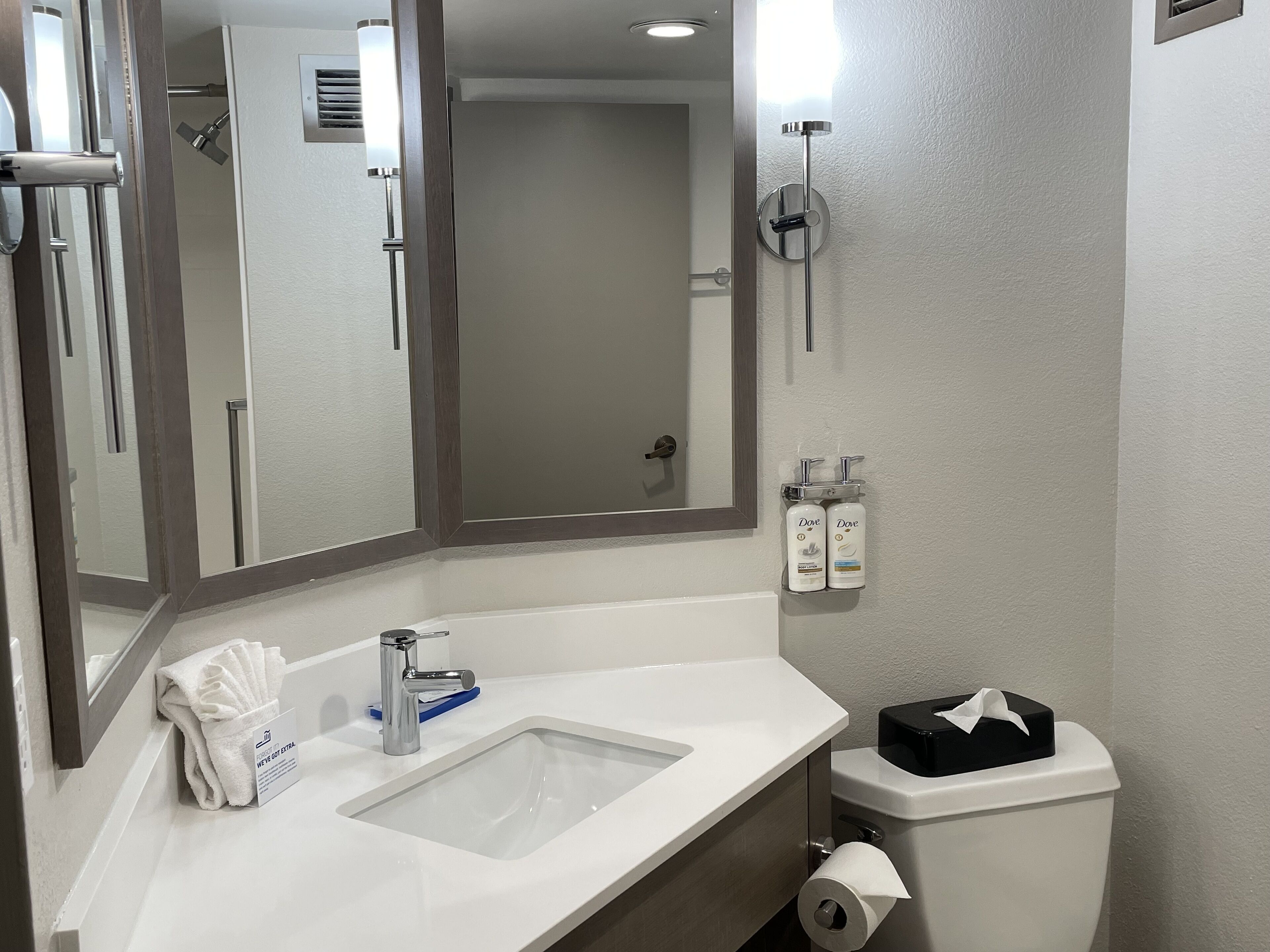 A bathroom with a white sink, a mirror, a towel rack, a toilet, and a shower.