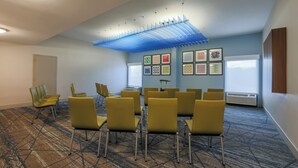 A conference room with yellow chairs arranged in a semi-circle, a patterned carpet, and a ceiling with a blue light fixture. - Holiday Inn Express Burlington by IHG (Burlington)