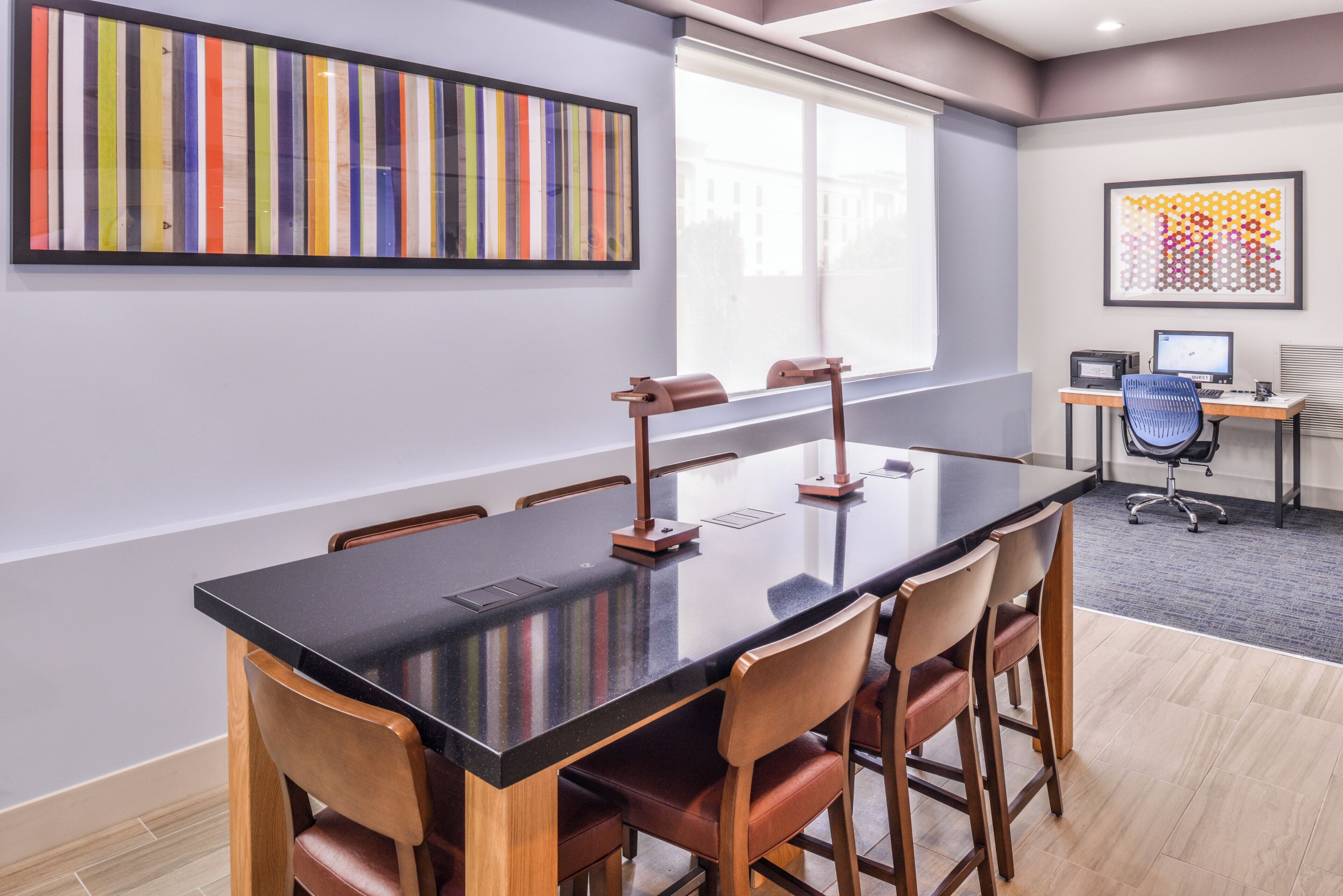 Une salle de conférence avec une longue table, des chaises, un bureau avec un ordinateur et des œuvres d’art accrochées aux murs.