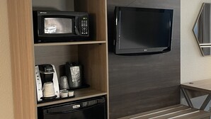A kitchenette with a microwave, coffee maker, and dishwasher. A flat-screen TV is mounted on the wall above the counter. - Holiday Inn Express Burlington by IHG (Burlington)