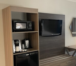 A kitchenette with a microwave, coffee maker, and dishwasher. A flat-screen TV is mounted on the wall above the counter.