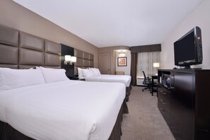 Quarto de hotel com duas camas, televisão, escrivaninha e uma cadeira.