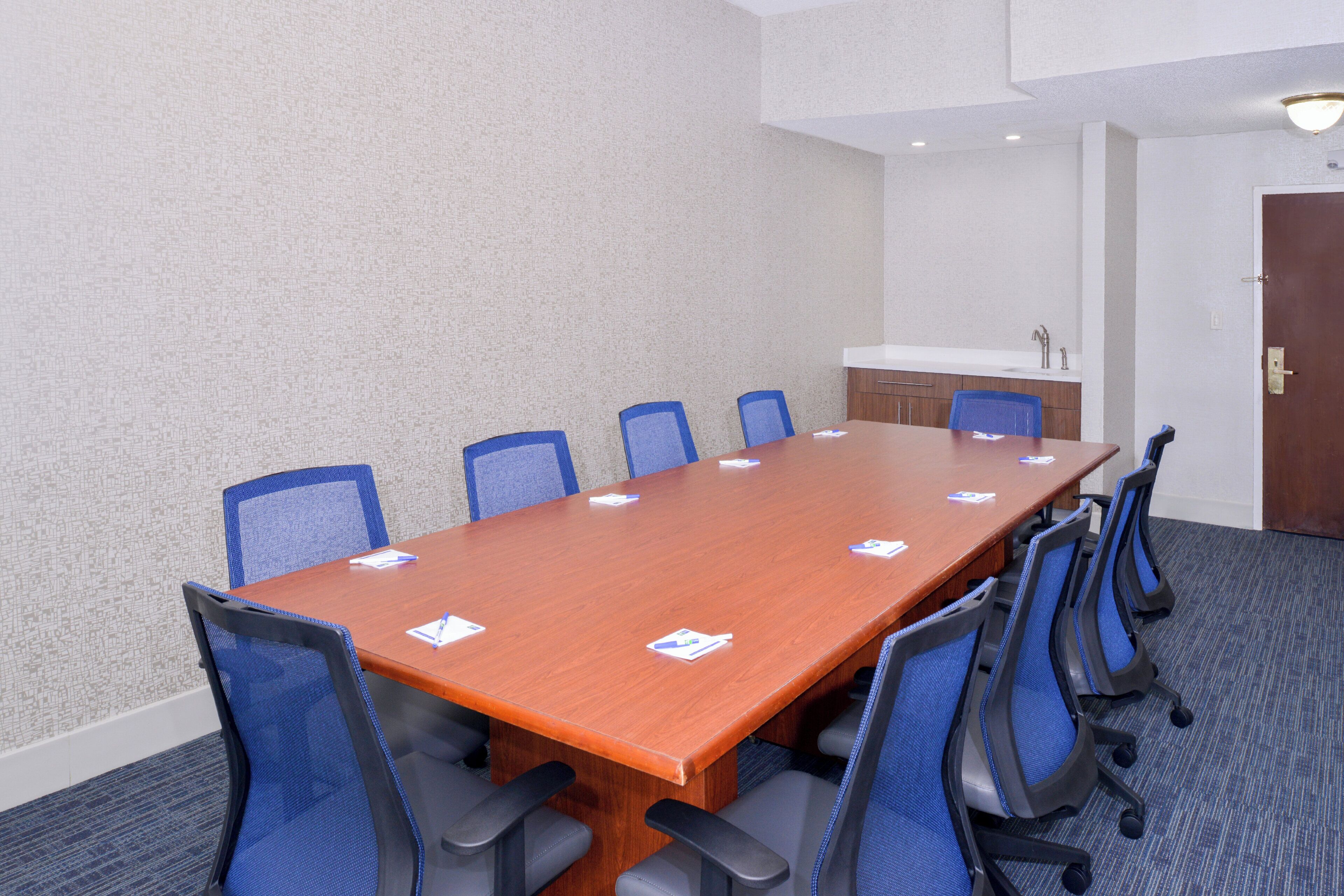 A conference room with a long table, six chairs, and a whiteboard.