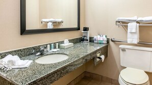A bathroom with a granite countertop sink, a mirror, a toilet, and a towel rack.