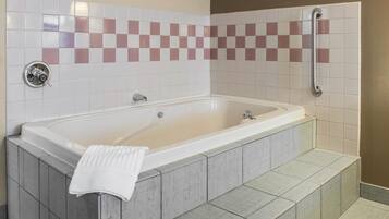 A modern bathroom with a freestanding bathtub, a handrail, and a tiled shower area.