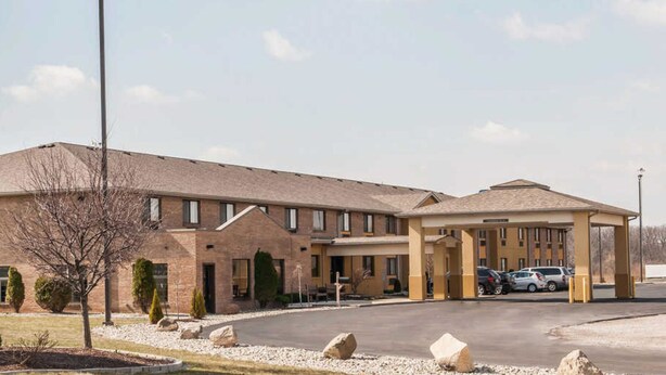 A multi-story hotel with a covered parking area and a landscaped driveway.