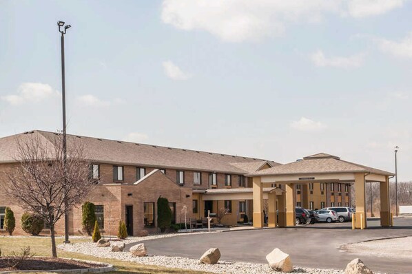 A multi-story hotel with a covered parking area and a landscaped driveway.