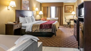 A hotel room with a bed, a desk, a television, a chair, and a bathroom.