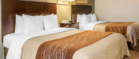 A hotel room with two beds, a headboard, bedside lamps, a nightstand, and a telephone.