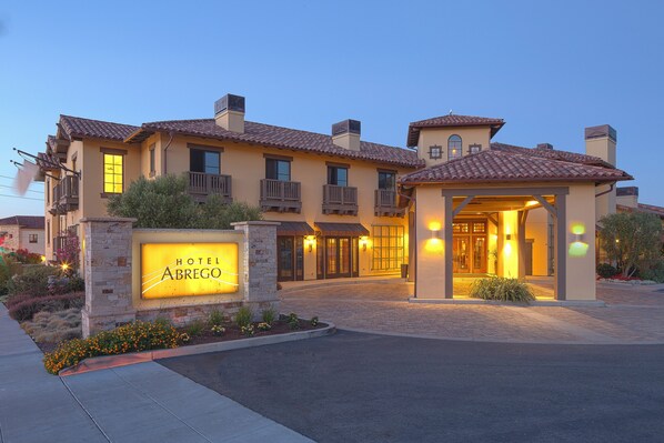 A hotel with a prominent entrance, a well-lit signboard, and a covered outdoor area.