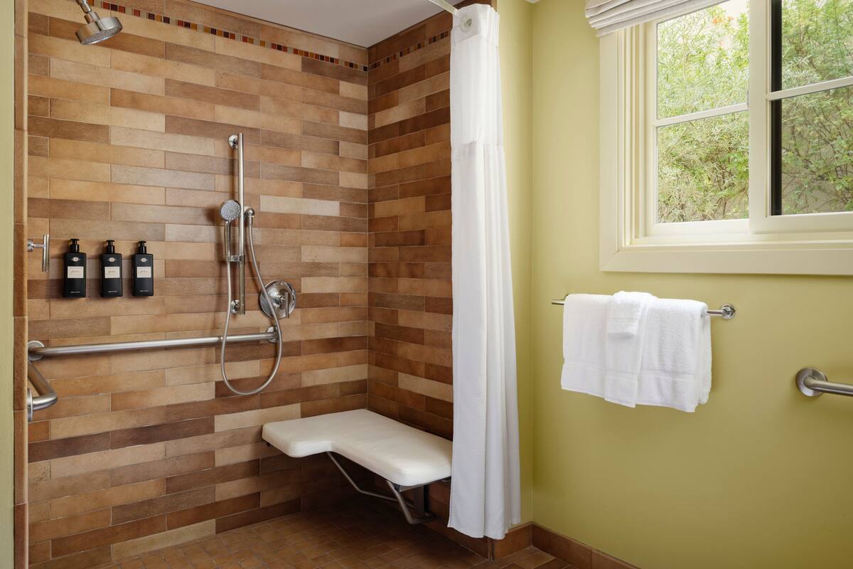 A bathroom with a shower, a bench, and a window.