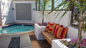 A pool area with a seating area, a patterned wall, and a small garden with flowers. - Hotel Abrego (Monterey)
