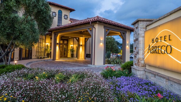 A hotel entrance with a covered patio, a flower garden, and a sign that reads "Hotel Abrego." - Hotel Abrego (Monterey)