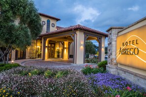 A hotel entrance with a covered patio, a flower garden, and a sign that reads "Hotel Abrego." - Hotel Abrego (Monterey)