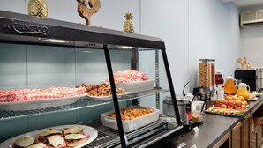 A buffet area with various food options, including pastries, fruits, and breakfast items. - Hotel Abrego (Monterey)