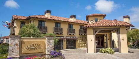 A hotel with a tiled roof, a stone entrance, and a signboard.