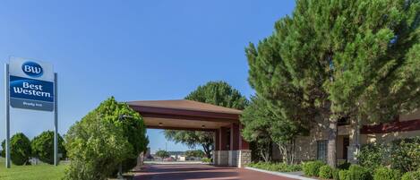 A hotel entrance with a covered walkway, a sign for 'Best Western Brady Inn', and surrounding greenery.