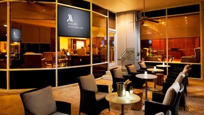 A Marriott Miami Dadeland hotel lobby with wicker furniture, a bar area, and a staircase leading to an upper level. - Marriott Miami Dadeland (Miami)
