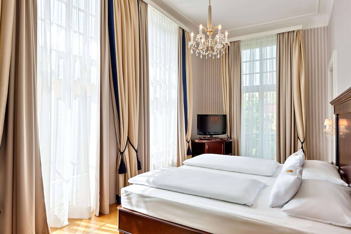 Ein Hotelzimmer mit einem großen Bett, einem Fernseher und einer Kandelaber.