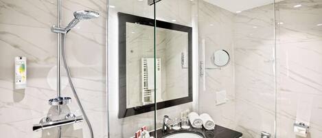 A modern bathroom with a glass-enclosed shower, a large mirror, a sink, and a toilet.