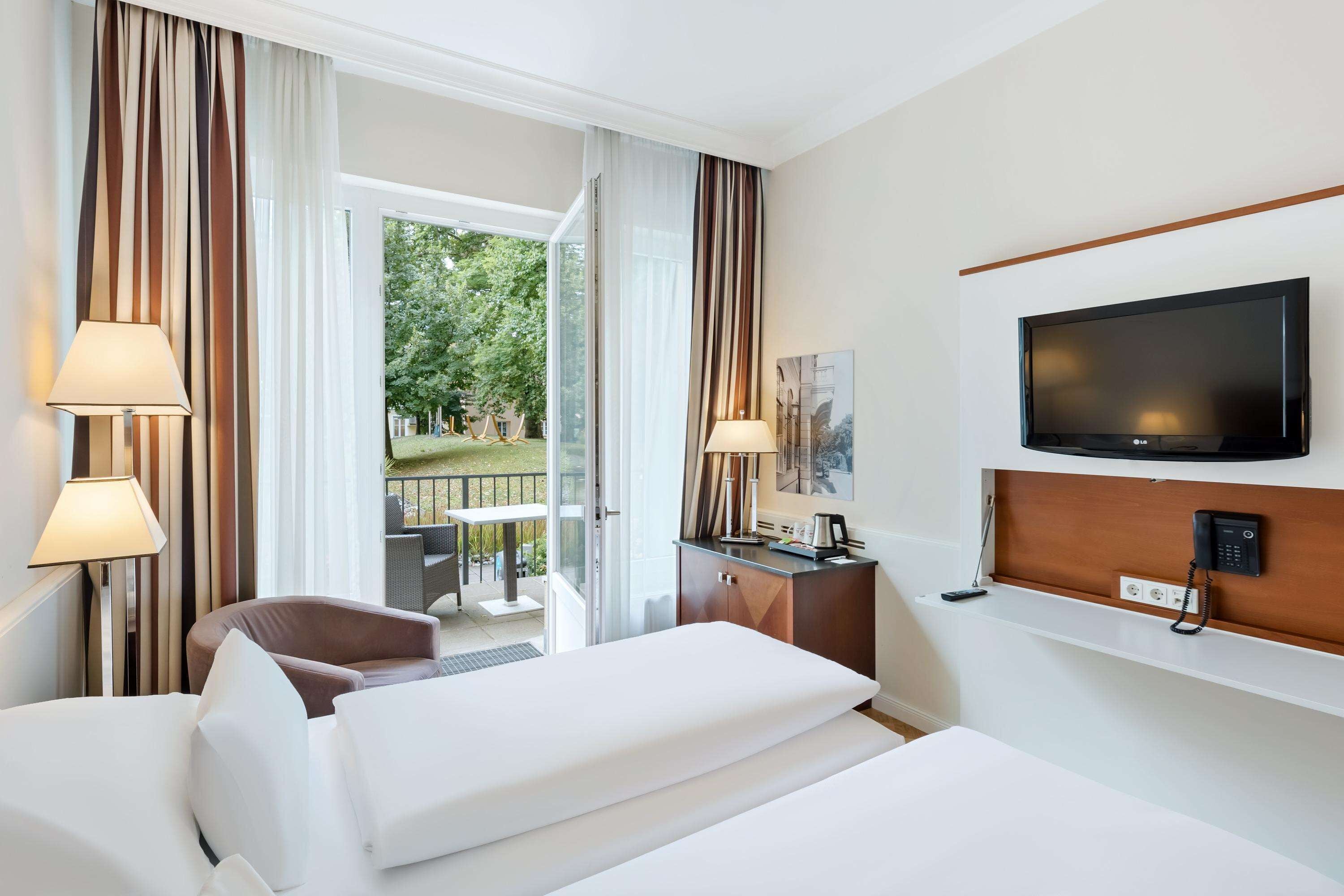 A hotel room with a bed, a desk, a television, and a view of the outdoors.