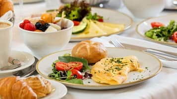 Impostazione per la colazione con croissant, insalata e una piastra di uova strapazzate.