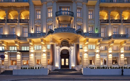 A grand hotel entrance with a symmetrical facade, multiple balconies, and a central entrance with steps leading up to a door.